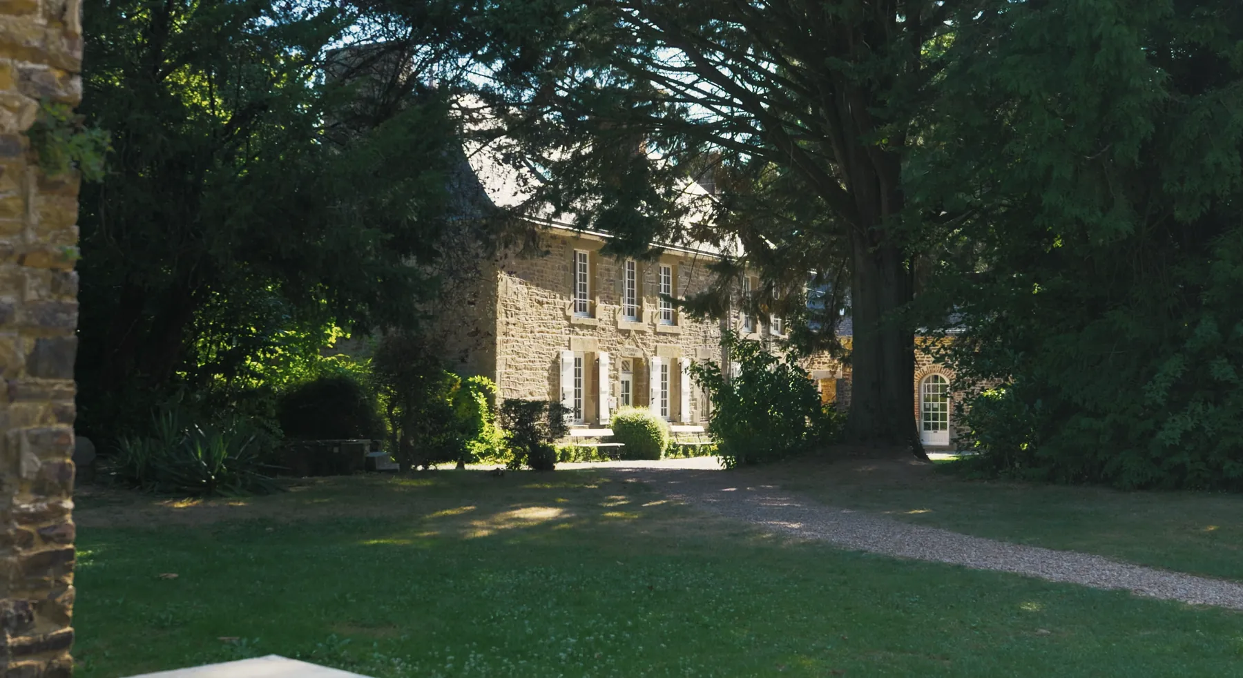 La demeure en pierre du Domaine du Haras de la Chaîne, à Saint-Pierre-des-Landes en Mayenne, entourée de grands arbres.