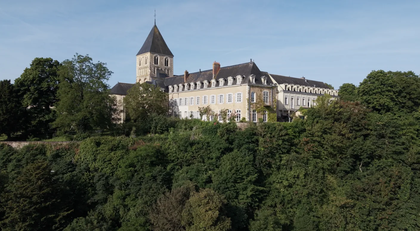 L'église et le prieuré de Château-Gontier, en Mayenne, dominant la vallée depuis leur promontoire boisé.